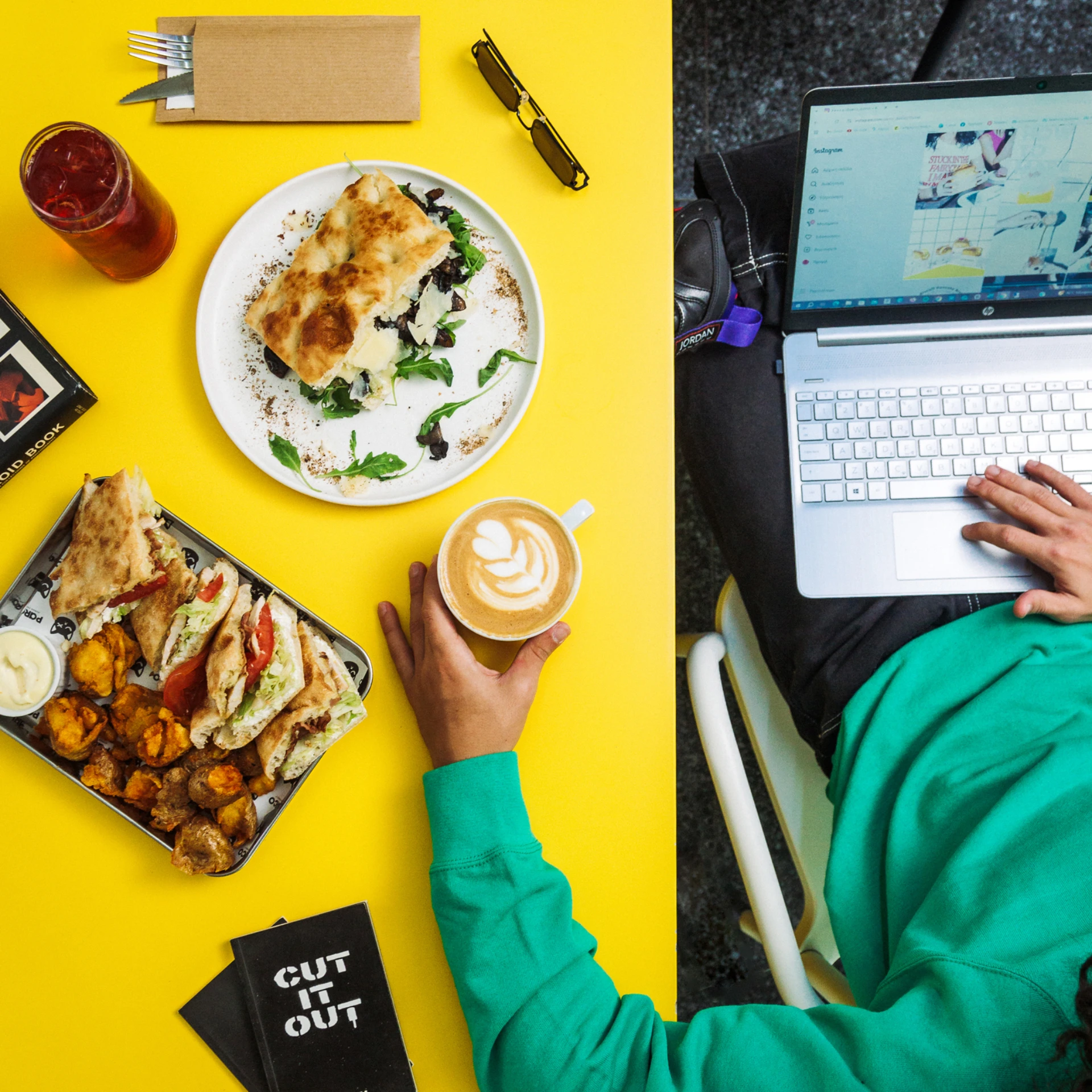 Casual scene of a man enjoying his food while working on a laptop in a cozy café